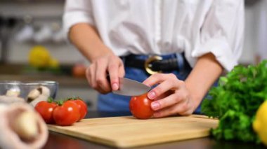 Kadın mutfakta domatesleri yavaş çekimde kesiyor. Salata için taze sebze.