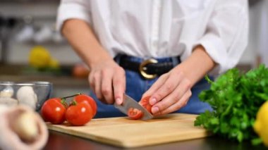 Kadın mutfakta domatesleri yavaş çekimde kesiyor. Salata için taze sebze.