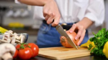 Kadın mutfakta domatesleri yavaş çekimde kesiyor. Salata için taze sebze.