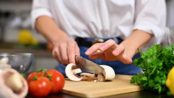 女性はスローモーションでキッチンのまな板にトマトを切っています サラダ用の新鮮な野菜 — ストック動画