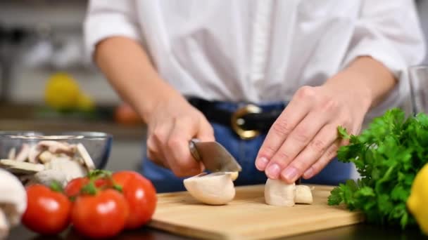 女性はスローモーションでキッチンのまな板にトマトを切っています サラダ用の新鮮な野菜 — ストック動画