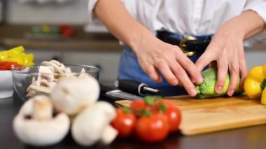 Kadın mutfakta domatesleri yavaş çekimde kesiyor. Salata için taze sebze.