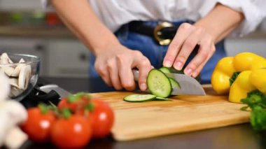 Kadın mutfakta domatesleri yavaş çekimde kesiyor. Salata için taze sebze.