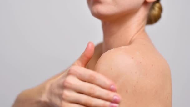スキンケア 乾燥肌にボディローションを広げてシャワー後の美しい女性 女性は肩に保湿剤を適用している — ストック動画