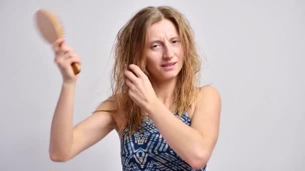 シャワー後の美しい女性は木製のヘアブラシで彼女の濡れた髪をブラッシングしています — ストック動画