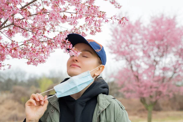 Hermosa Mujer Quita Una Máscara Médica Disfrutar Floración Del Árbol —  Fotos de Stock