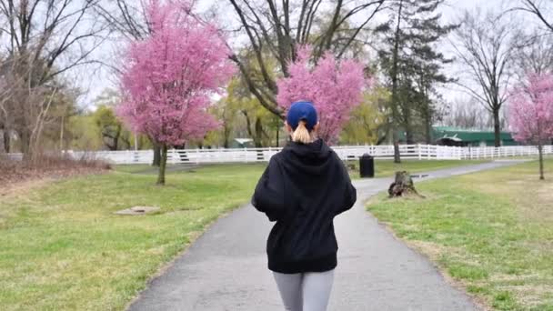 女性は公園で走っている 春の自然の中で外の若いランナーの訓練 — ストック動画