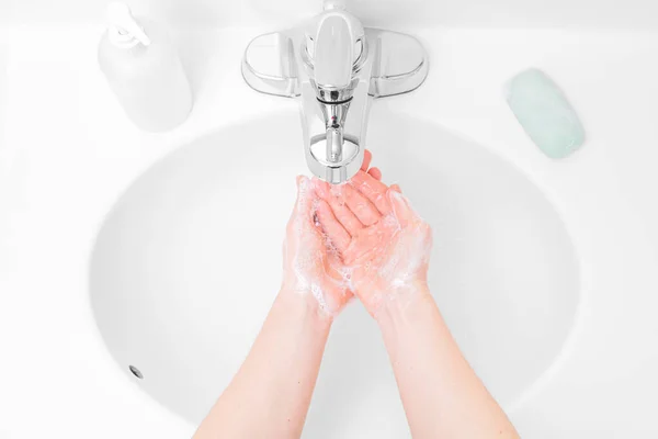 女は手を石鹸で洗うシンクの水の下で — ストック写真