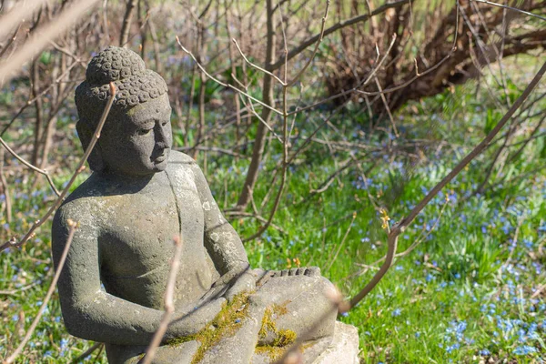 Stone Buddha sculpture in the garden early spring.