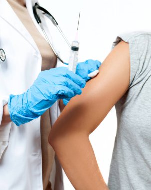 Koruyucu eldivenli doktor, Coronavirüs enfeksiyonundan korunmak, aşı olmak ve tedavi olmak için hastanın koluna koronavirüs aşısı enjekte ediyor.