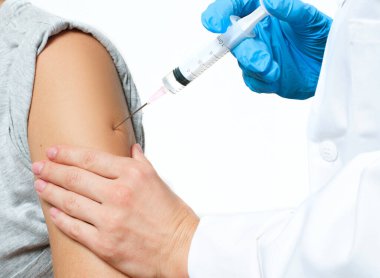 Koruyucu eldivenli doktor, Coronavirüs enfeksiyonundan korunmak, aşı olmak ve tedavi olmak için hastanın koluna koronavirüs aşısı enjekte ediyor.
