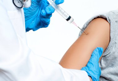 Koruyucu eldivenli doktor, Coronavirüs enfeksiyonundan korunmak, aşı olmak ve tedavi olmak için hastanın koluna koronavirüs aşısı enjekte ediyor.