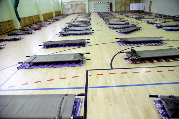 refugee camp in school sports hall full with stretcers
