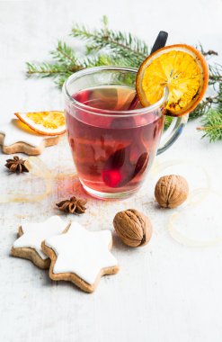 Beyaz ahşap arka plan üzerinde krema, çam, portakal dilimleri, tarçın, anason, ceviz ve altın kurdele ile ev yapımı tereyağı fındık yıldız şeklinde çerezler. Bir fincan dut çayı. Noel dekorasyonu.