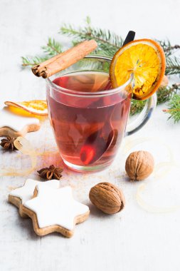 Beyaz ahşap arka plan üzerinde krema, çam, portakal dilimleri, tarçın, anason, ceviz ve altın kurdele ile ev yapımı tereyağı fındık yıldız şeklinde çerezler. Bir fincan dut çayı. Noel dekorasyonu.