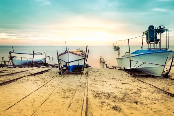 Vecchi pescherecci posati sulla riva del mare. Colorato tramonto sopra la spiaggia sabbiosa di Ravda, Bulgaria . — Foto Stock