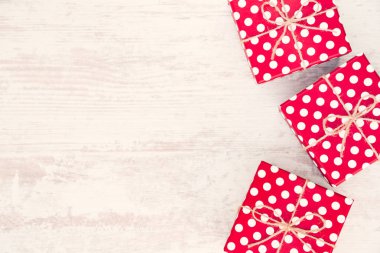 Beyaz ahşap arka plan üzerinde kırmızı noktalı hediye kutuları dağınık. Kopya alanı.