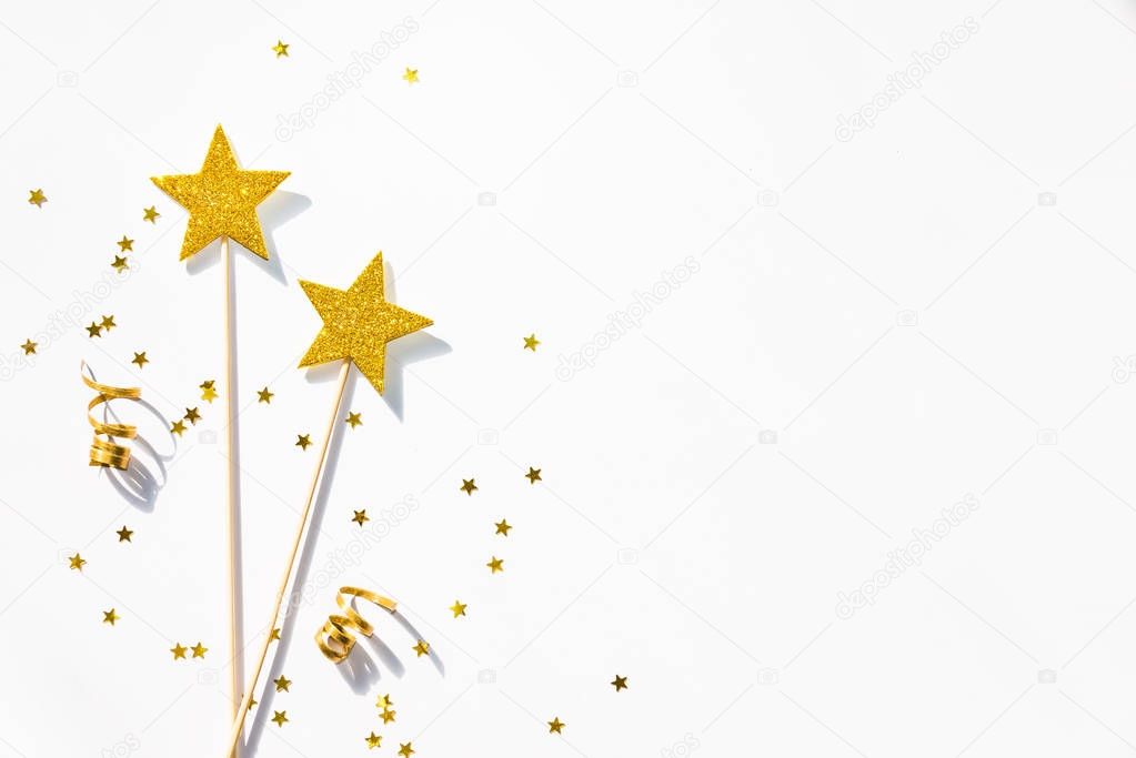 Two golden party magic wands, sequins and ribbons on a white background. Copy space. 