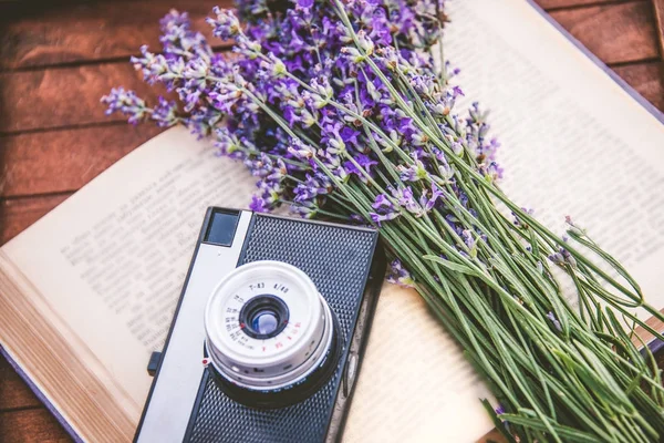 Frisch geschnittene Lavendelblüten und eine alte Fotokamera über einem offenen Buch.. — Stockfoto