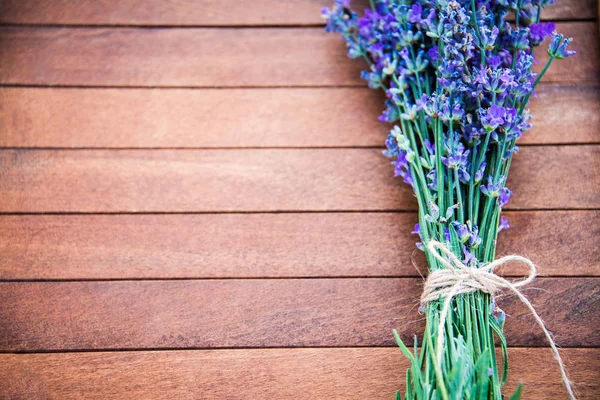 Top view of a lavender bouquet laid over a brown wooden background. Copy space. — Stock Photo, Image