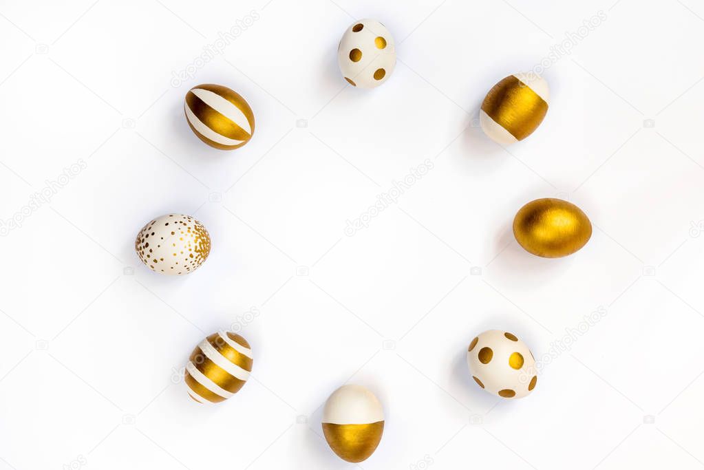 Top view of easter eggs colored with golden paint in differen patterns arranged in circle. Various striped and dotted designs. White background. Copy space.