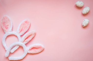Üstten Görünüm Paskalya yumurtaları ve pembe bir arka plan üzerinde iki beyaz tüylü tavşan kulakları. Kopya alanı.