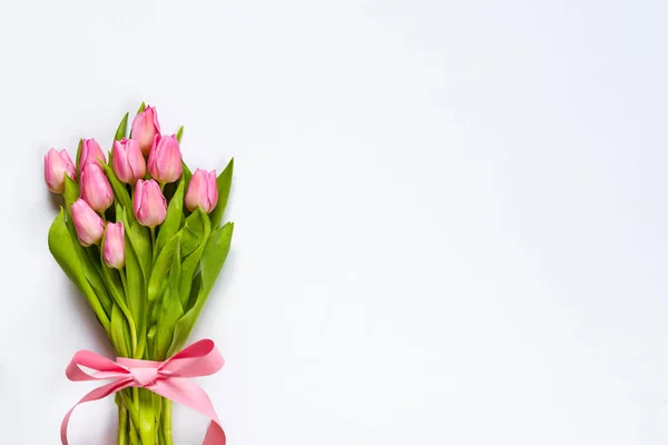 Top view of pink tulips bouquet, wrapped with pink ribbon over white background. Copy space. — Stock Photo, Image