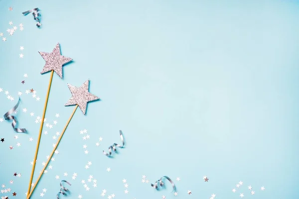 Dos varitas mágicas de fiesta de plata, lentejuelas y cintas sobre un fondo azul. Copiar espacio . — Foto de Stock