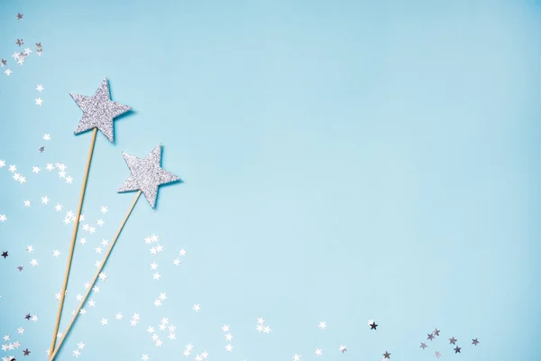 Dos varitas mágicas de plata y lentejuelas dispersas sobre un fondo azul. Copiar espacio . — Foto de Stock