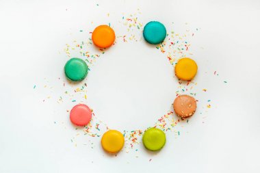 Renkli macaroons görünümünü üst ve beyaz arka plan üzerinde daire içinde düzenlenmiş sprinkles şeker. Kopya alanı. 