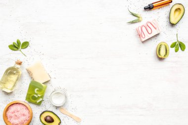 Turunçgiller, otlar, çim tohumları, aloe ve gerekli yağlarla sıralanmış organik sabun ve kozmetik ürünlerinin üst görüntüsü. Beyaz rustik arkaplan, kopyalama alanı.