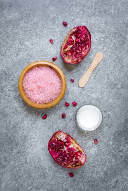 Gri taş zemin üzerinde organik nar ve kozmetik ürünlerinin üst görünümü.