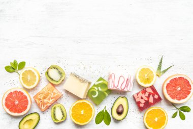 Turunçgiller, otlar, chia tohumları ve aloe ile düzenlenmiş çeşitli el yapımı organik sabunların üst görüntüsü. Beyaz rustik arkaplan, kopyalama alanı.