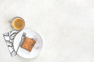 Bir fincan kahvenin üst görüntüsü ve beyaz kırsal arka planda kek ile tatlı tabağı..