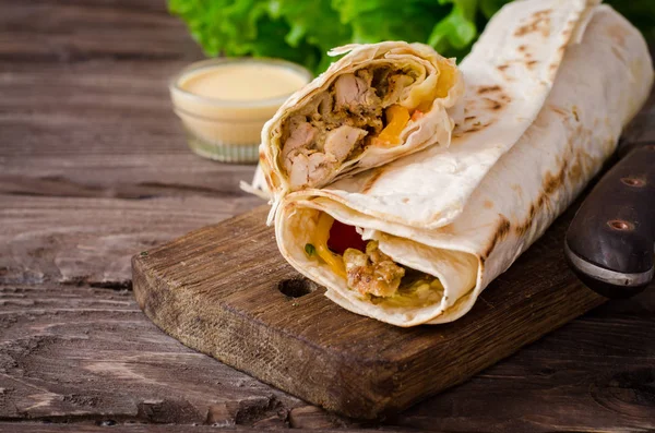 Shawarma chicken roll in a pita with fresh vegetables and cream sauce on wooden background. Selective focus — Stock Photo, Image