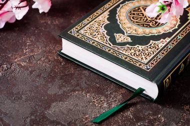 İslami kitap Kur'an ve Kerim demektir Arapça Hat ile koyu arka plan bahar çiçekleri brunch. Teşekkürler kavramı. Seçici odak