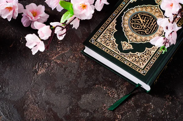 Livro Islâmico Alcorão e flores de primavera brunch em fundo escuro com caligrafia árabe que significa o Alcorão Sagrado. Conceito de soar. Foco seletivo — Fotografia de Stock