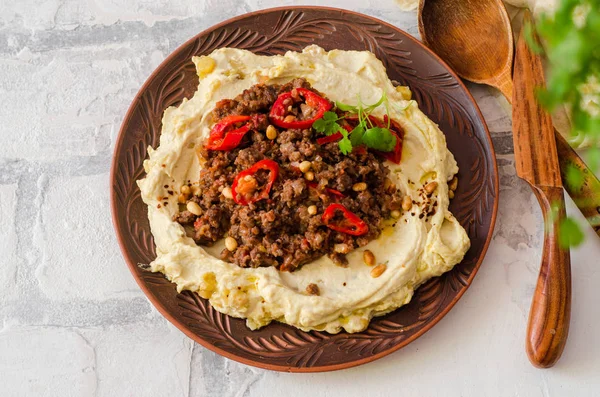 Hummus cremoso con carne picante de cordero picada en tazón de barro sobre fondo de piedra. Comida Ramadán. Vista superior — Foto de Stock