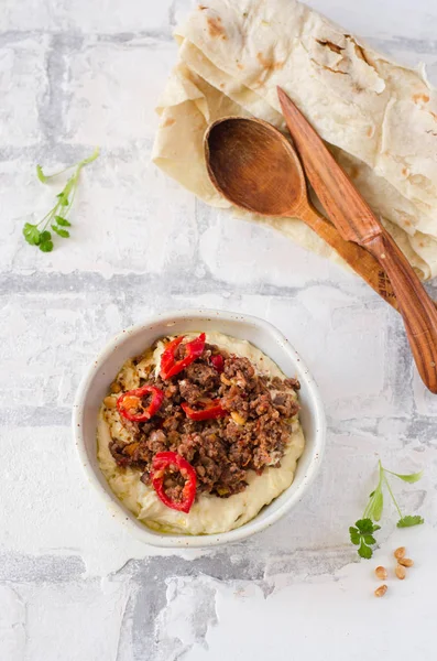 Hummus crémeux avec du mouton épicé haché viande dans un bol en argile sur fond de pierre. Alimentation du Ramadan . — Photo