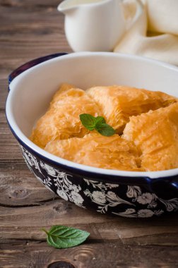 Ev yapımı baklava ahşap masanın üzerine krema tatlım sirup ile doldurulmuş. Doğu tatlılar. Ramazan gıda