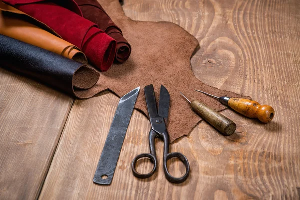 Set of leather craft tools on wooden background. Workplace for shoemaker.