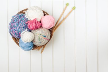 Örgü iplik topları ve iğneler Beyaz ahşap zemin üzerinde.