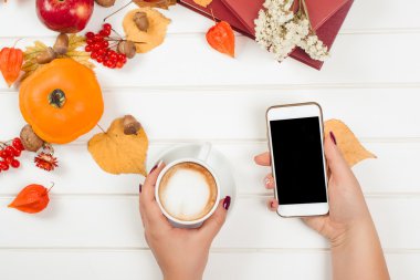 Kahve molası, cep telefonu kullanarak. Sonbahar arka plan Üstten Görünüm.