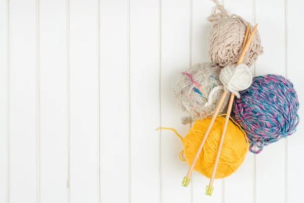 Bolas de fio de tricô e agulhas no fundo de madeira branco . — Fotografia de Stock