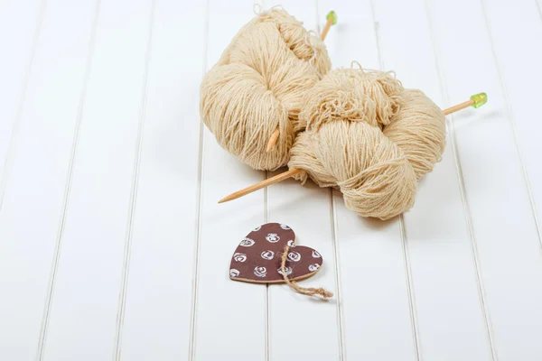 Natural woolen yarn with wood needles on white wooden background. — Stock Photo, Image