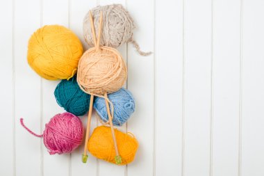 Örgü iplik topları ve iğneler Beyaz ahşap zemin üzerinde.