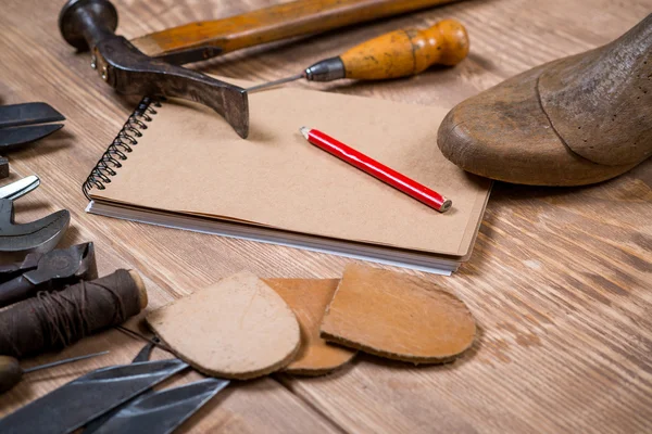 एक लकड़ी की पृष्ठभूमि पर जूता निर्माता के लिए उपकरण, नोटबुक, पेंसिल का सेट . — स्टॉक फ़ोटो, इमेज