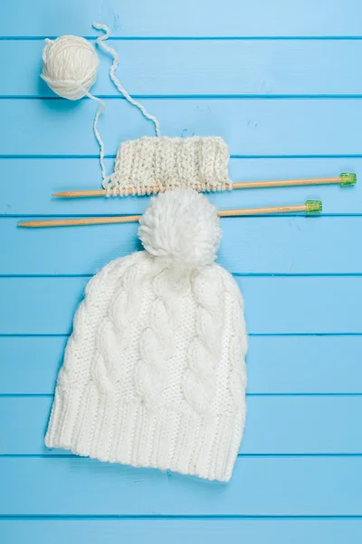 Knitted white scarf and hat on blue wooden background. — Stock Photo, Image