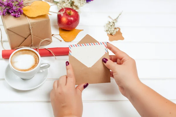 Female hands hold gift card. Gift boxes, cup of cappuccino on autumn background. — Stock Photo, Image