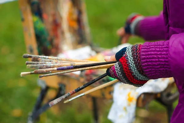 Female artist's hand hold paintbrushes and painting a sketch of